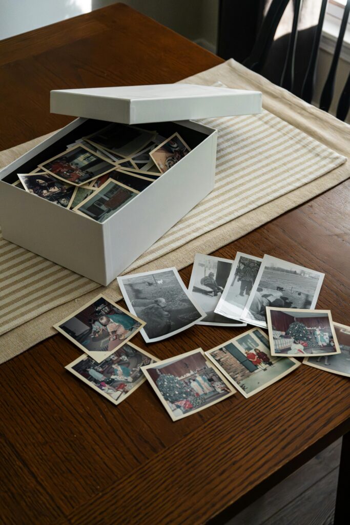 Open box of vintage family photos on a wooden table, evoking nostalgia.